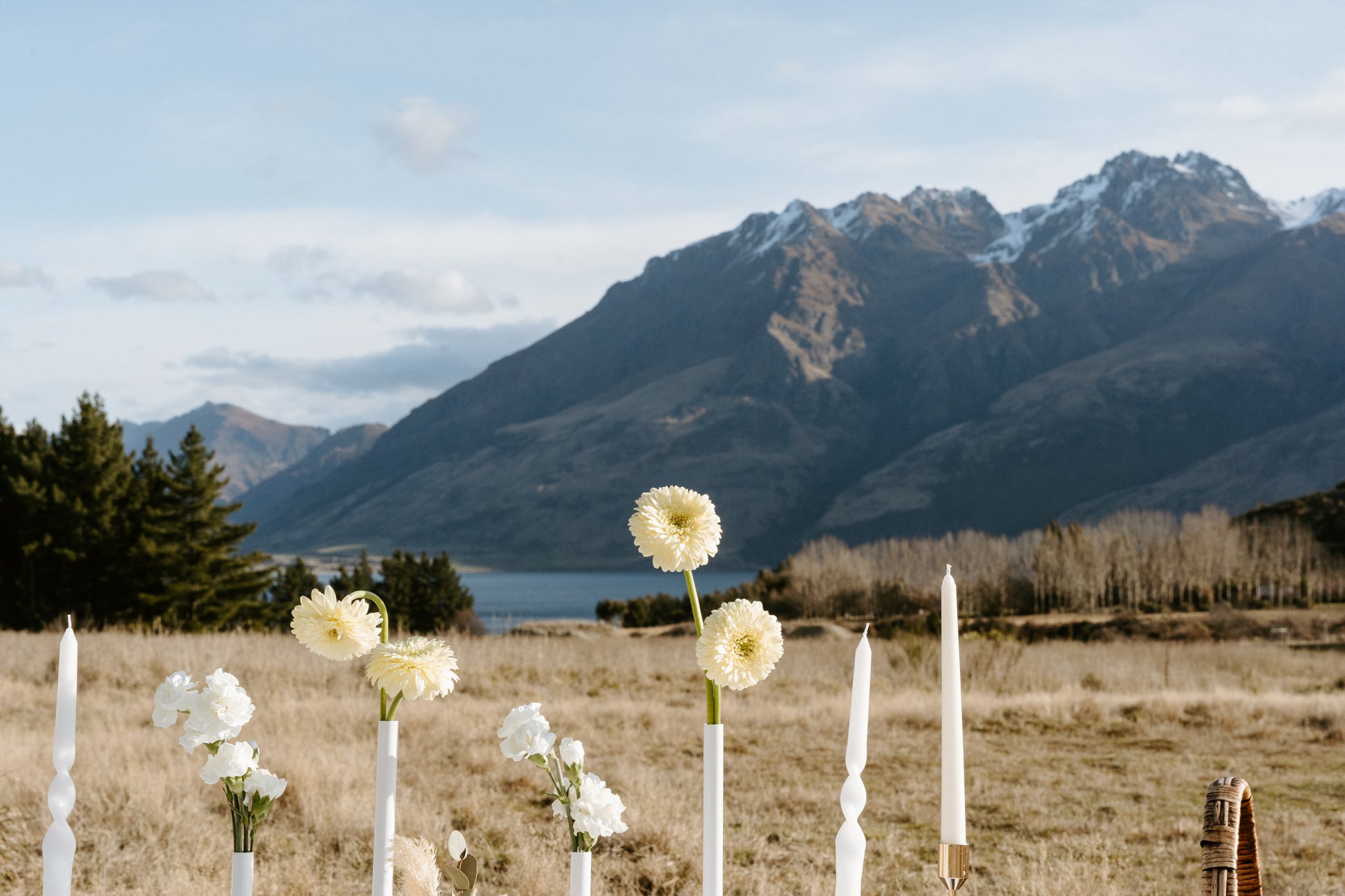 Floral arrangements and candles in a field with mountains in the background