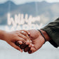 Two people holding hands with a mountainous background