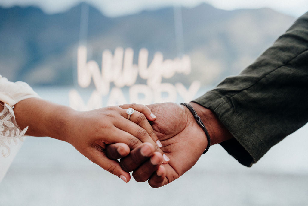 Two people holding hands with a mountainous background