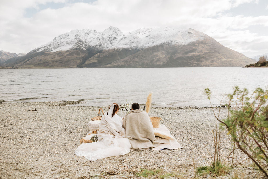 Romantic beach elopement picnic for two on a beach with mountains in the distance.