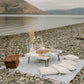 Romantic picnic set up on a rocky beach with mountains in the background