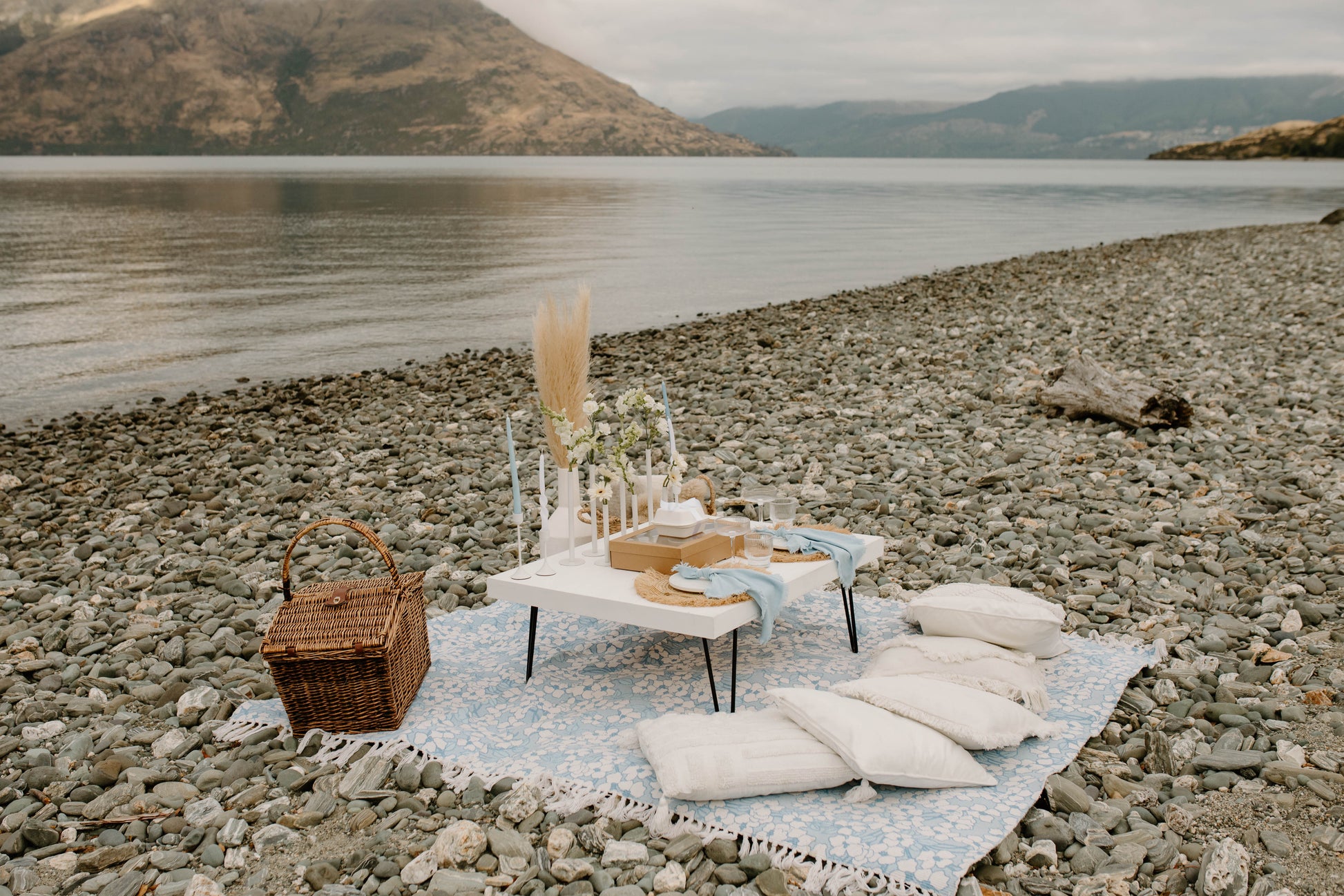 Romantic picnic set up on a rocky beach with mountains in the background