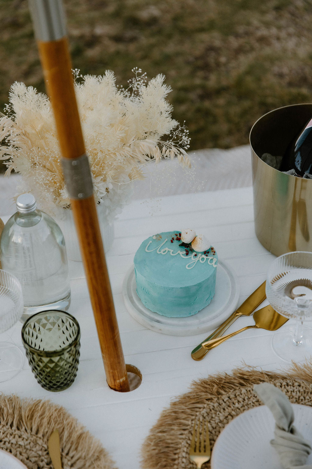 Teal cake with a 'I love you' message on a luxurious picnic table setting