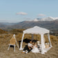 Newly engaged couple sitting under a white canopy with mountains in the background, admiring the engagement ring.